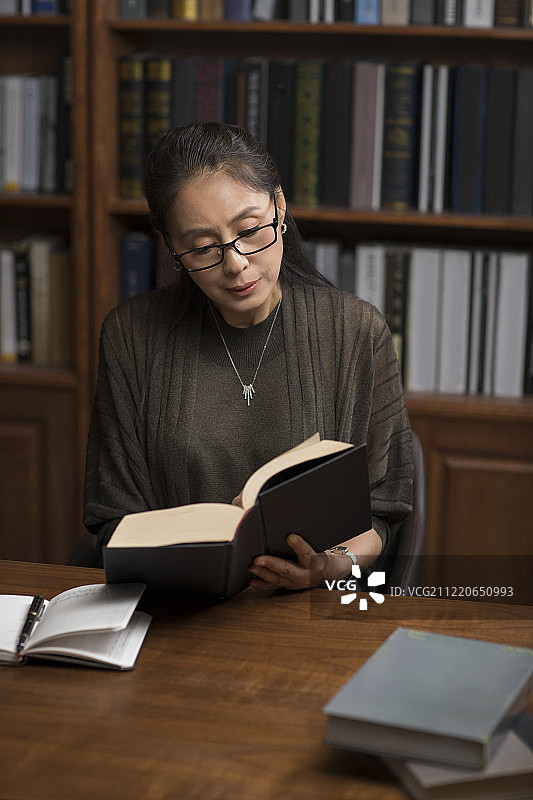 优雅的中年女士在书房读书图片素材