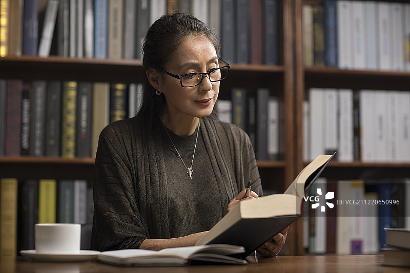 优雅的中年女士在书房读书图片素材