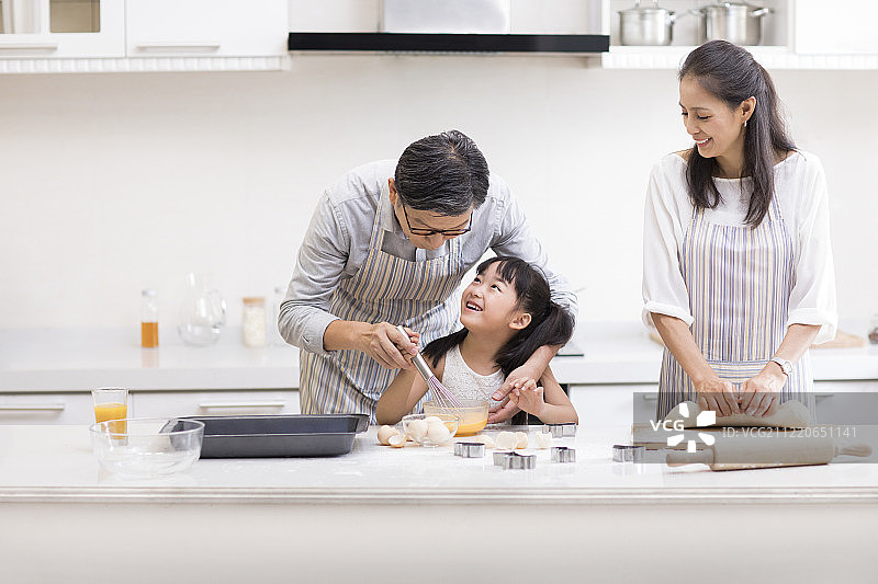 快乐小女孩和爷爷奶奶在厨房制作饼干图片素材