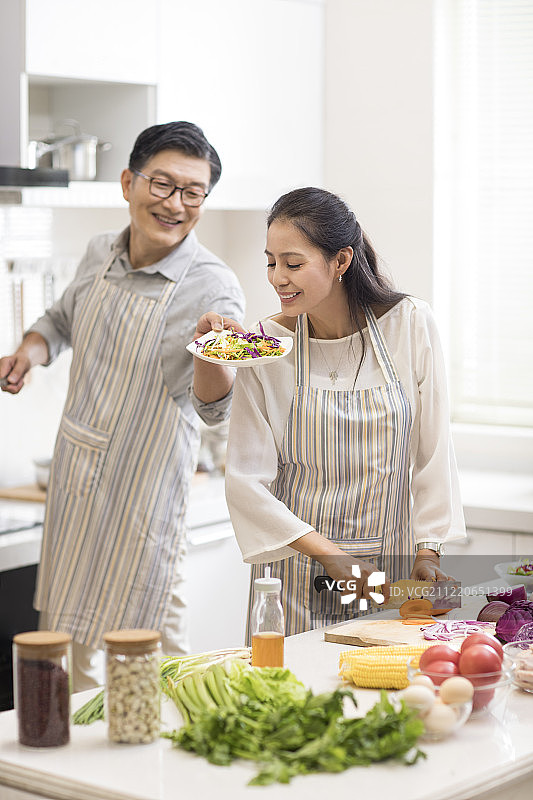 快乐中年夫妇在厨房做饭图片素材