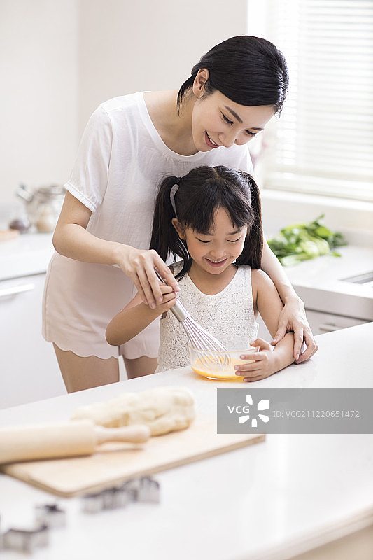 快乐小女孩和妈妈在厨房做饭图片素材