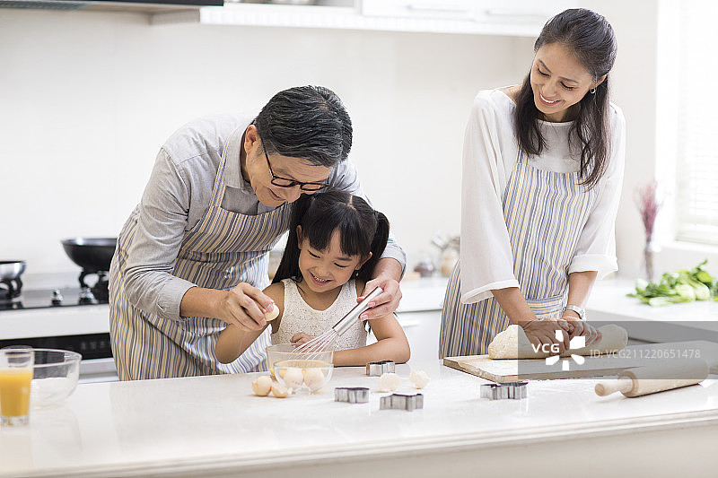 快乐小女孩和爷爷奶奶在厨房做饭图片素材