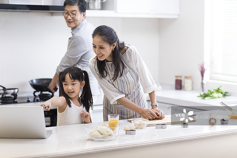 快乐小女孩和爷爷奶奶在厨房制作饼干图片素材