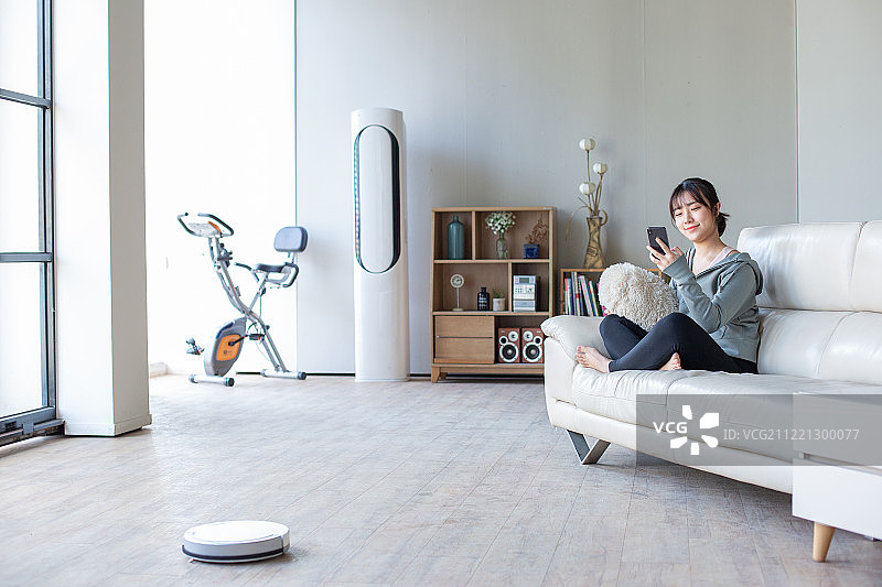客厅、沙发、坐姿、智能手机、微笑、扫地机器人、蓝牙图片素材