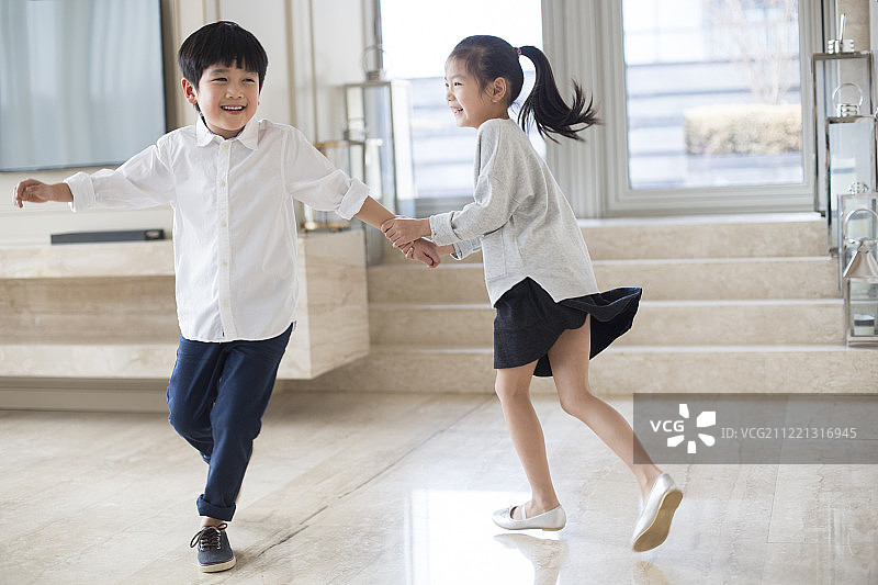 快乐的兄妹俩在客厅奔跑图片素材