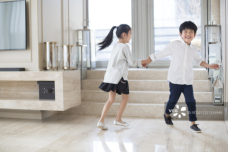 快乐的兄妹俩在客厅奔跑图片素材