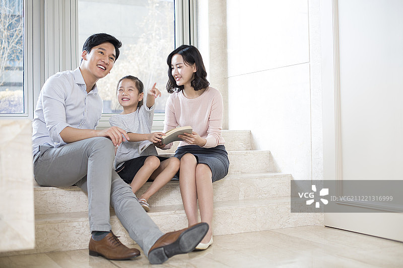 快乐的年轻家庭在客厅看书图片素材