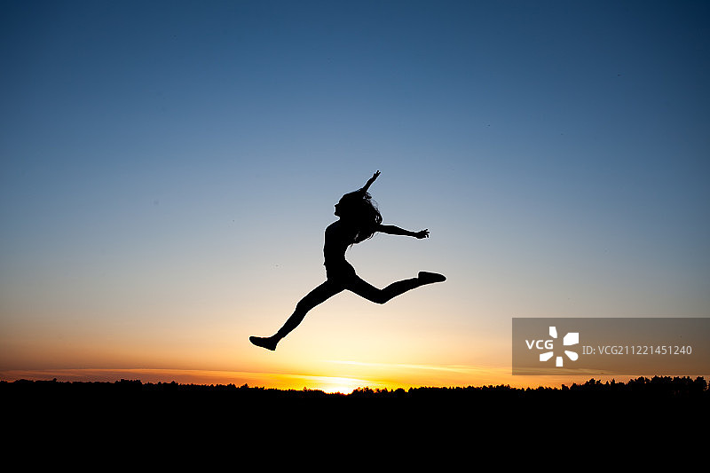 日落天空下的女性舞者剪影图片素材