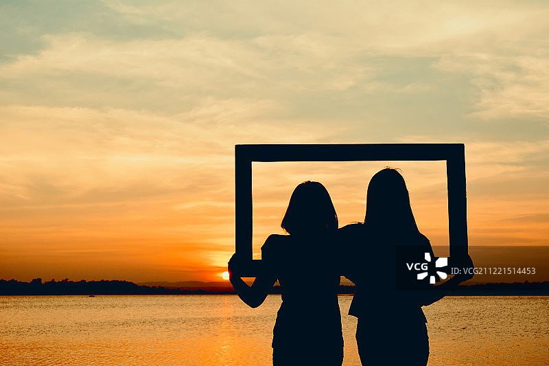 情人节概念：日落时分，手持相框的女子轮廓图片素材