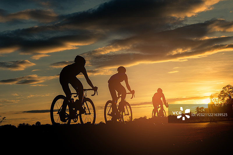 在日落时骑自行车的男人与橙蓝色天空背景抽象剪影背景图片素材