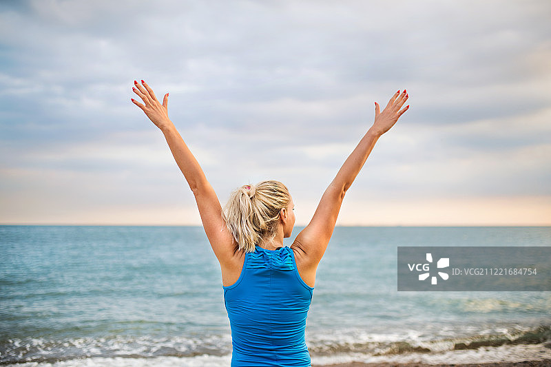 身穿蓝色运动服的年轻女子在海滩跑步的背影图片素材