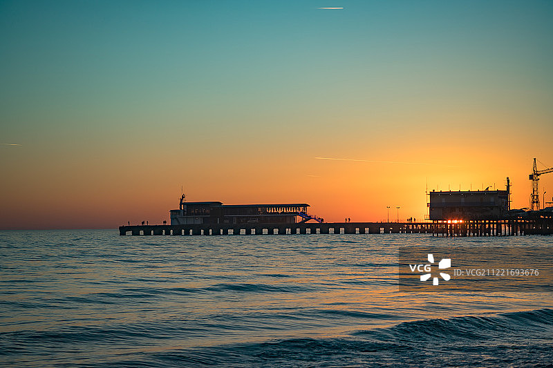 城市海上码头上的亮橙色日落图片素材