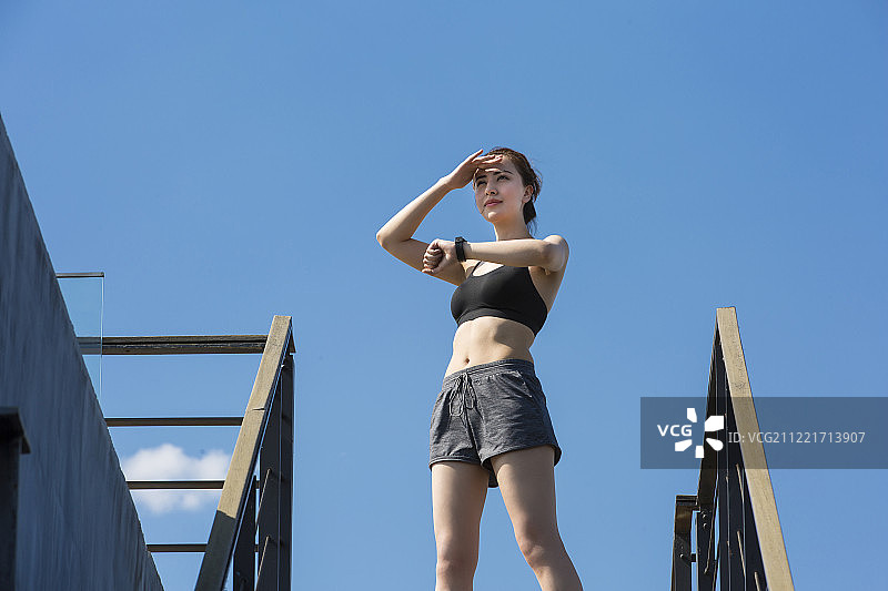 青年女子在户外运动后看智能手表图片素材