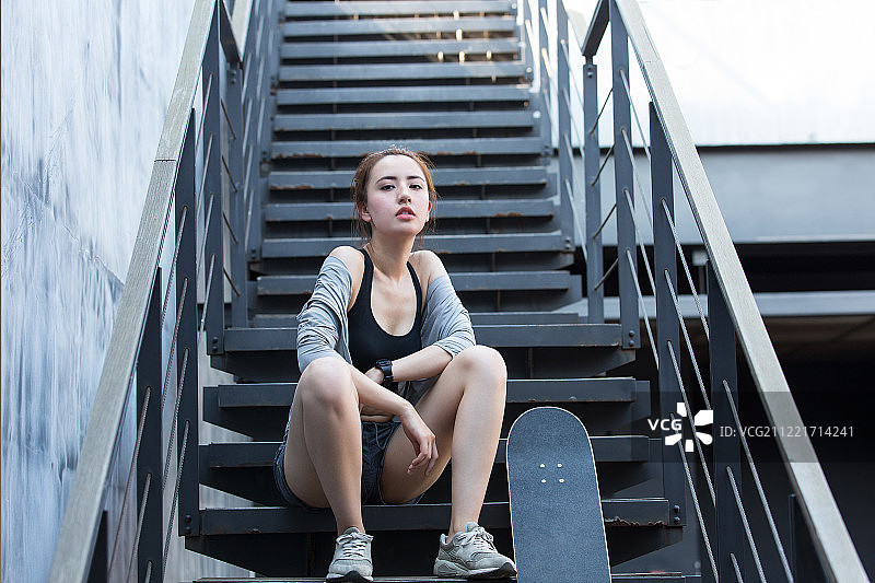 青年女子在户外滑板运动后休息图片素材