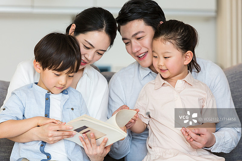 爸爸、妈妈在客厅给女儿、儿子读书讲故事图片素材