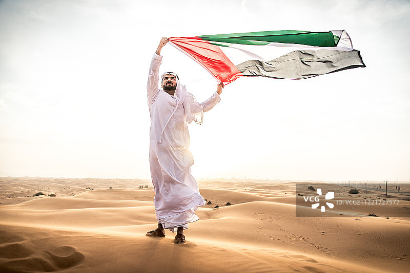 穿着阿联酋传统服装走在沙漠中的阿拉伯男人图片素材