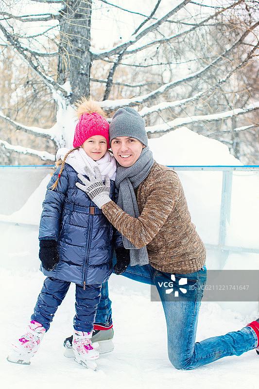 可爱的小女孩和快乐的父亲在户外滑冰场上图片素材