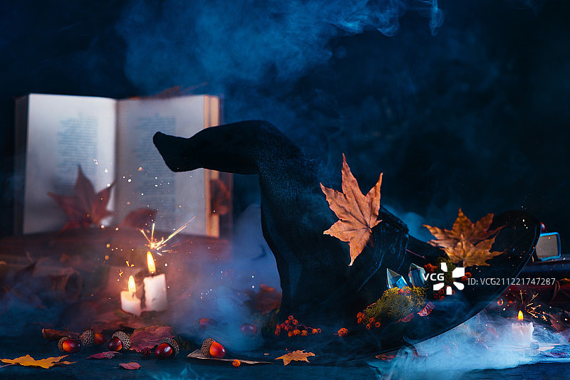 在怪异的静物中，女巫帽与蜡烛、烟雾和火花在一起，神秘而神奇的场景图片素材