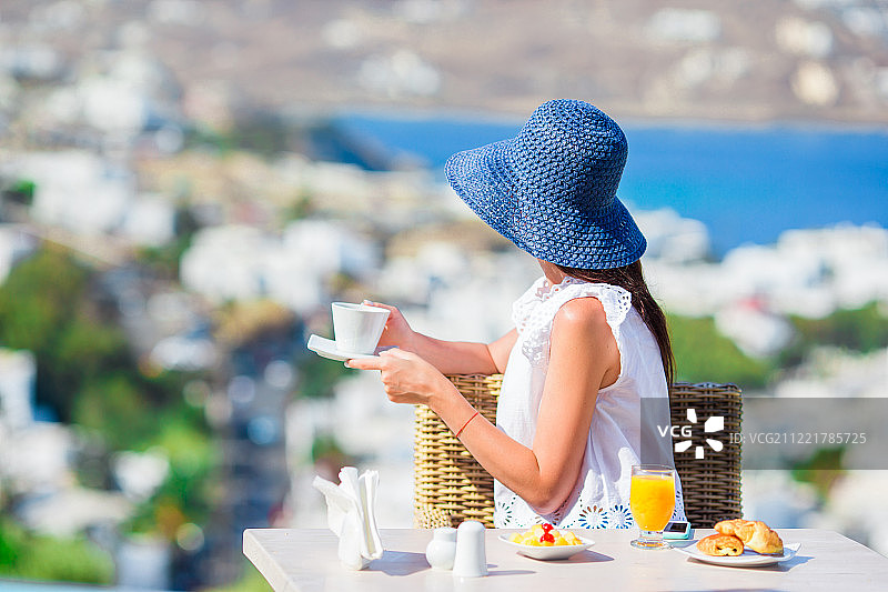 在米科诺斯小镇户外咖啡馆享用早餐的优雅女士图片素材