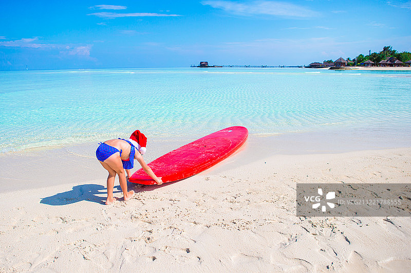 戴圣诞帽的小女孩在热带海滩度假图片素材