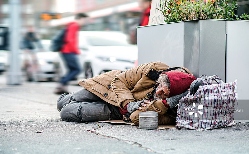在城市户外躺在地上乞讨捐款的流浪乞丐图片素材