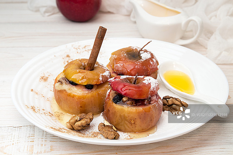 白盘子上蜂蜜核桃馅烤苹果图片素材