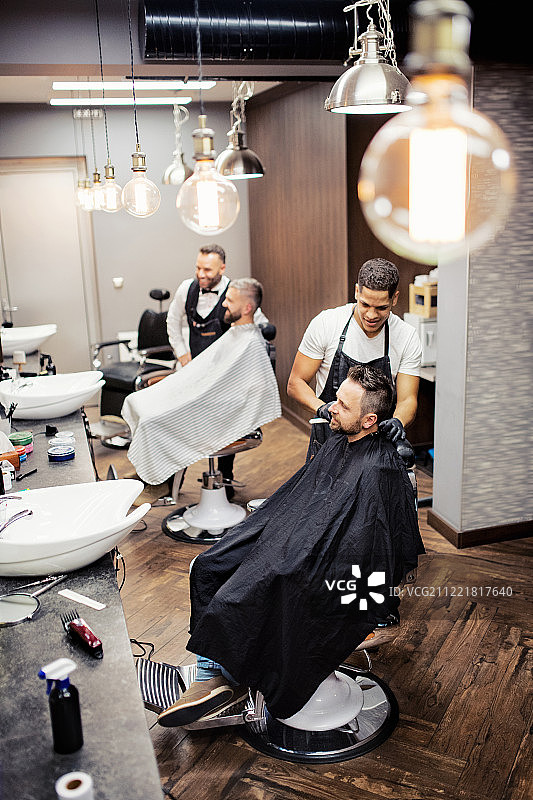 顾客在理发店拜访理发师和发型师的高角度视图图片素材
