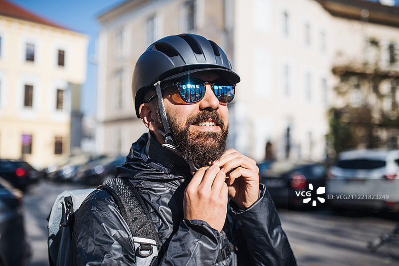戴墨镜的快递员在城市里运送包裹图片素材