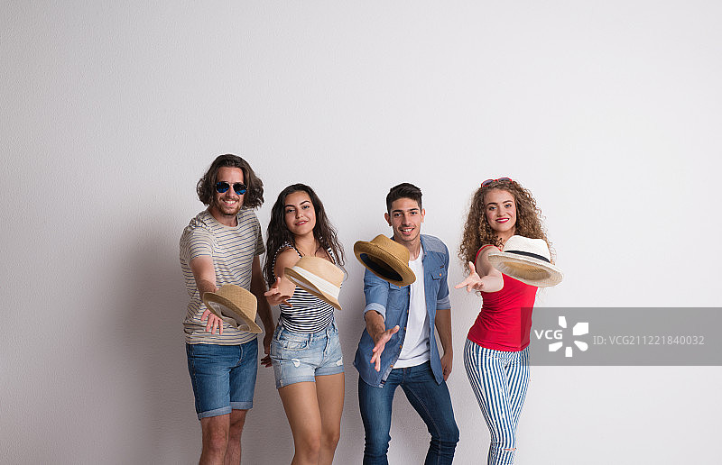 一群戴着帽子的快乐年轻朋友在工作室合影图片素材