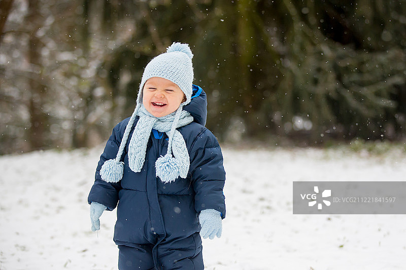 在冬日雪地里玩耍的可爱幼儿男孩图片素材