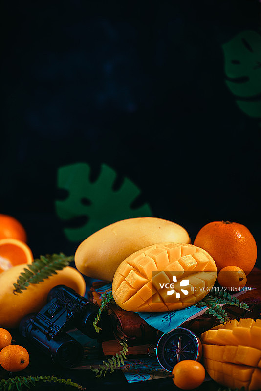 芒果特写与橙子、金橘和其他热带水果深色背景，带有文案空间图片素材