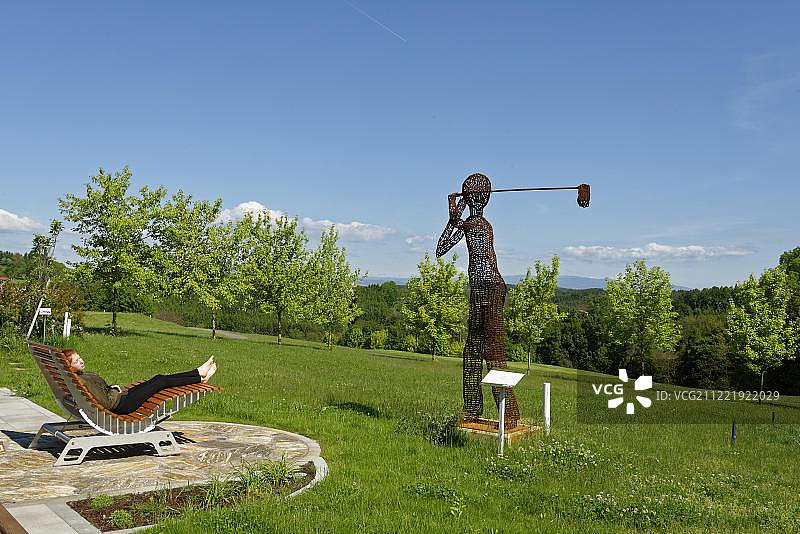 年轻女孩在奥地利放松身心，背景是高尔夫球手雕塑图片素材