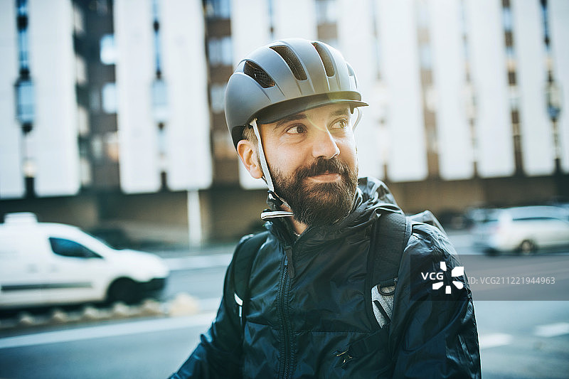 戴自行车头盔的男快递员在城市送包裹图片素材