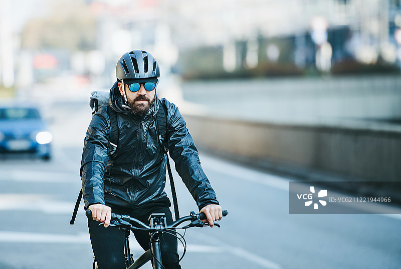 在城市中运送包裹的男性自行车快递员的正面图。复制空间。图片素材