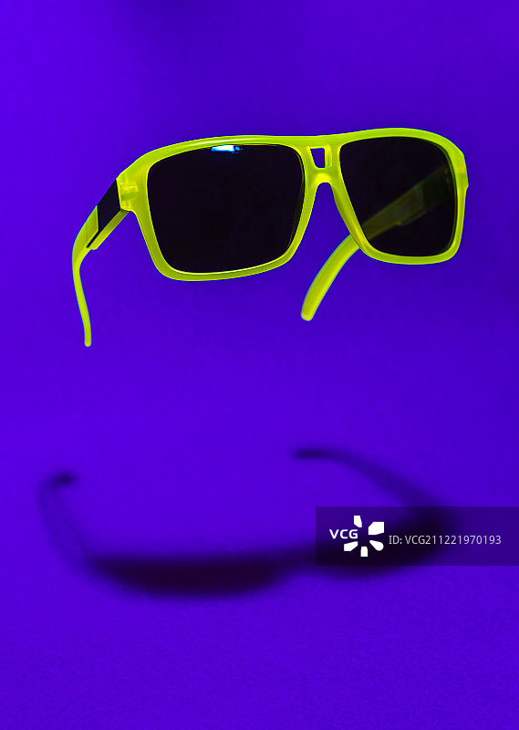 紫色背景上漂浮的绿色太阳镜图片素材