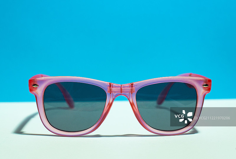 粉色亮面太阳镜，粉蓝色背景，夏季图片素材