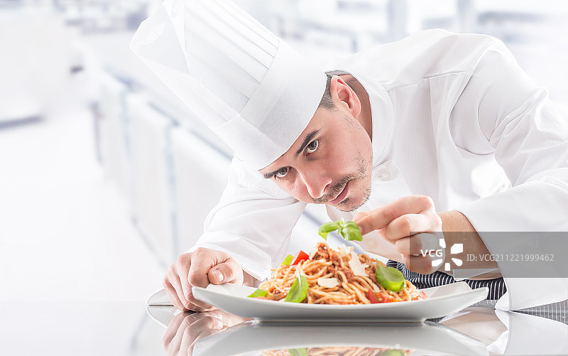 餐厅厨房里，厨师用手准备和装饰食物。厨师准备肉酱意大利面图片素材