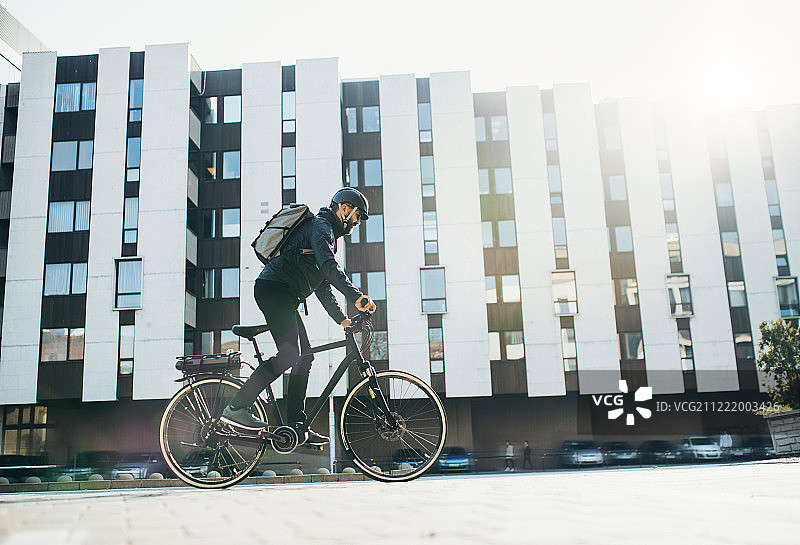 骑自行车的快递员在城市里送包裹，有文案空间图片素材