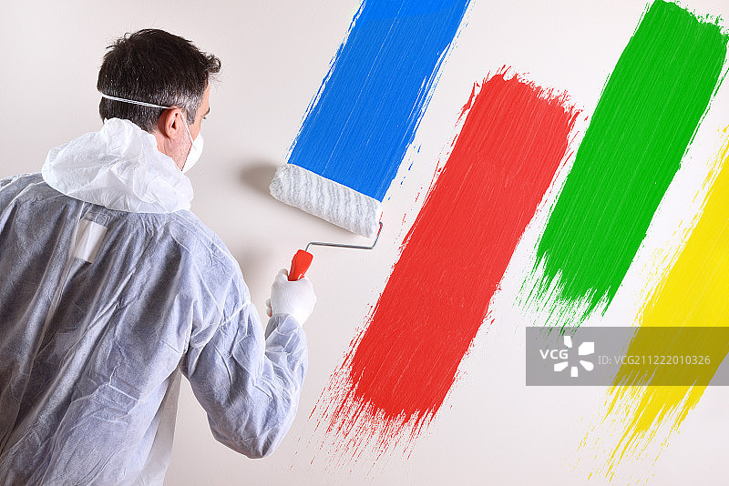身穿工作服的油漆匠和涂有四种颜色的墙壁图片素材