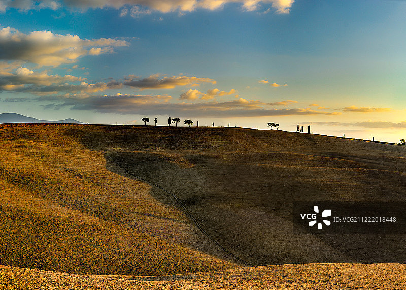 托斯卡纳山丘的日落，黄色山坡和蓝色天空图片素材