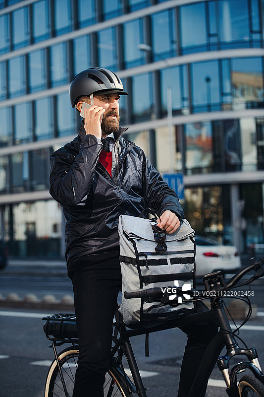 骑自行车在城市送包裹的男快递员正在打电话图片素材