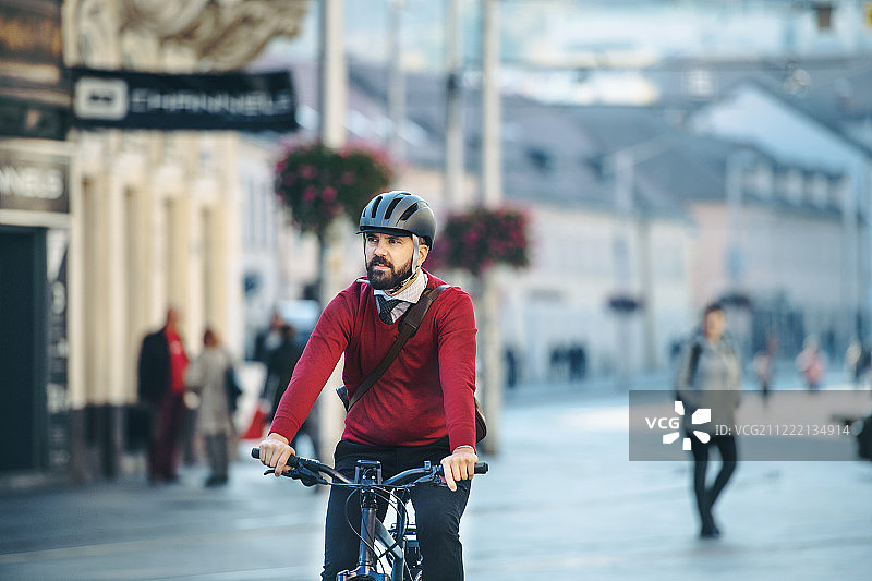时髦的商务人士骑着电动自行车在城市中通勤上班图片素材