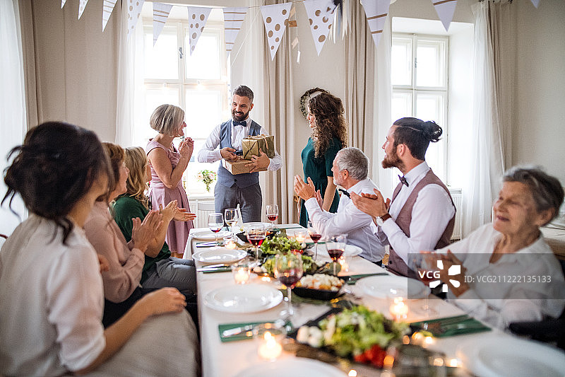 年轻夫妇在家庭生日聚会上给母亲送礼物图片素材