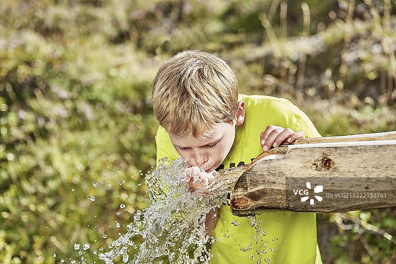 金发男孩在喷泉喝水，奥地利蒂罗尔州齐勒ertal山谷 Hintertux图片素材