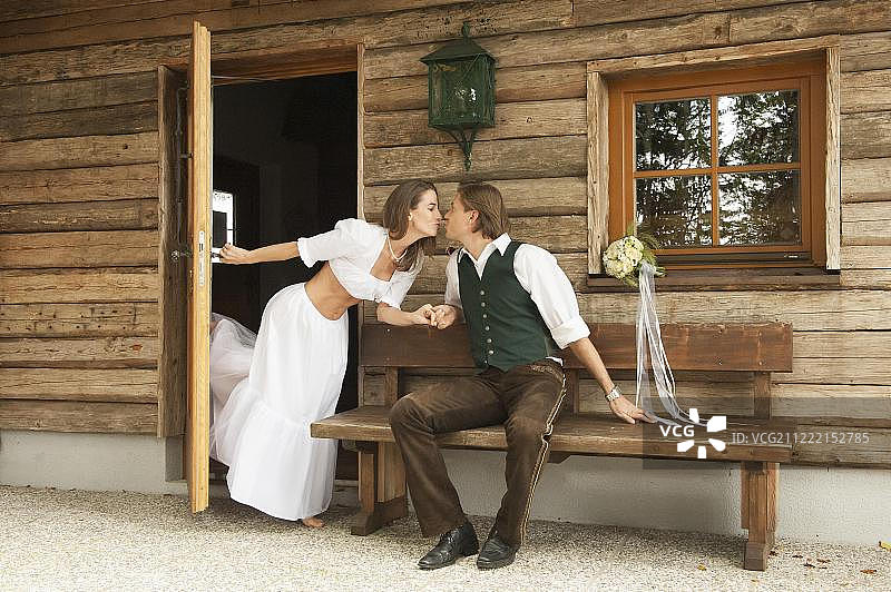 在阿尔卑斯山小屋前的婚礼夫妇图片素材