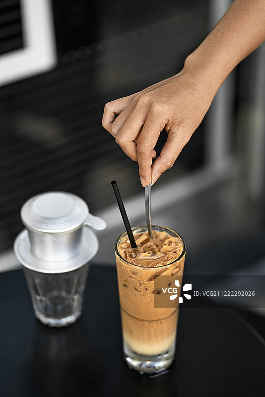 在户外咖啡馆用勺子搅拌冰咖啡的女孩图片素材