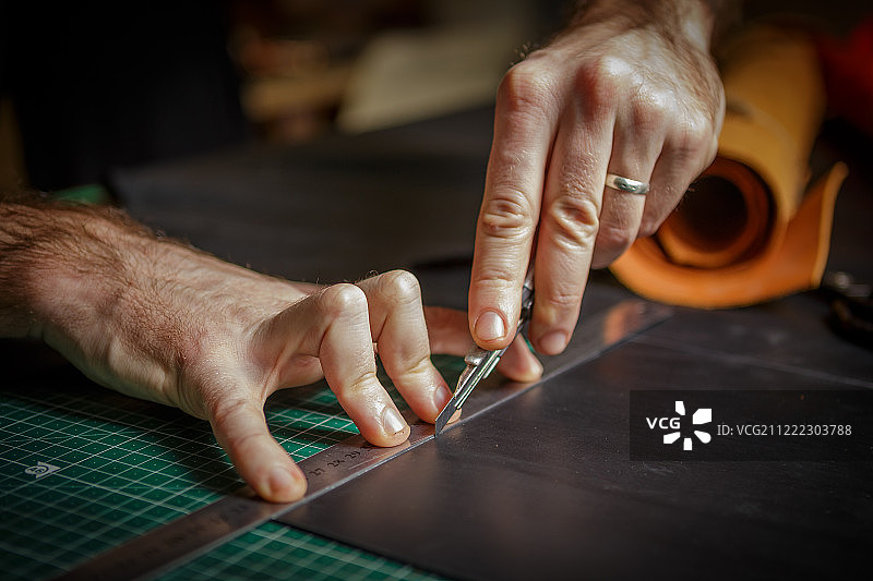 工匠在皮革工坊用刀切割皮革图片素材