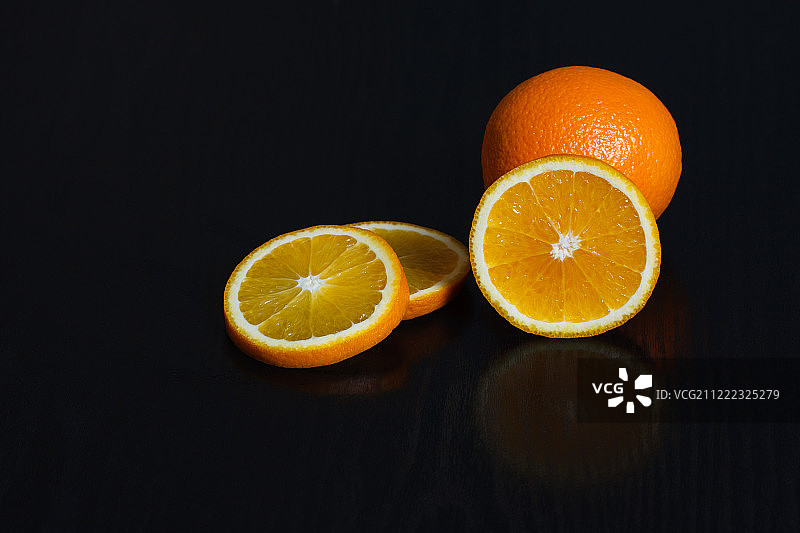 黑色背景上的半个和整个橙子，侧视图，留有文字空间图片素材