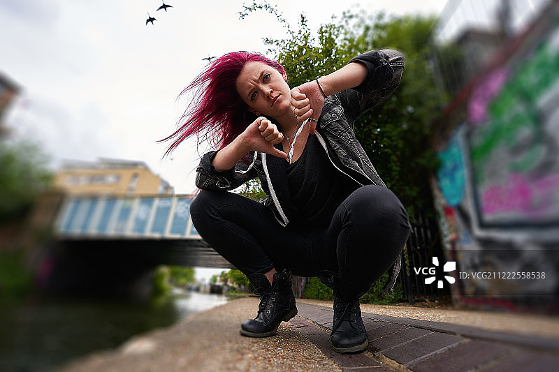 女人轻蔑地竖起大拇指，鸟儿飞过图片素材