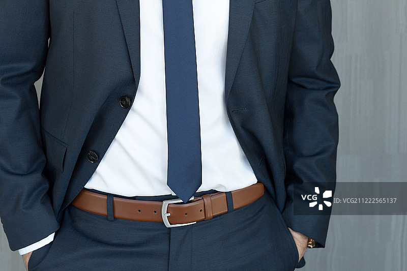 身穿经典海军蓝西装，双手紧握的商务男士图片素材
